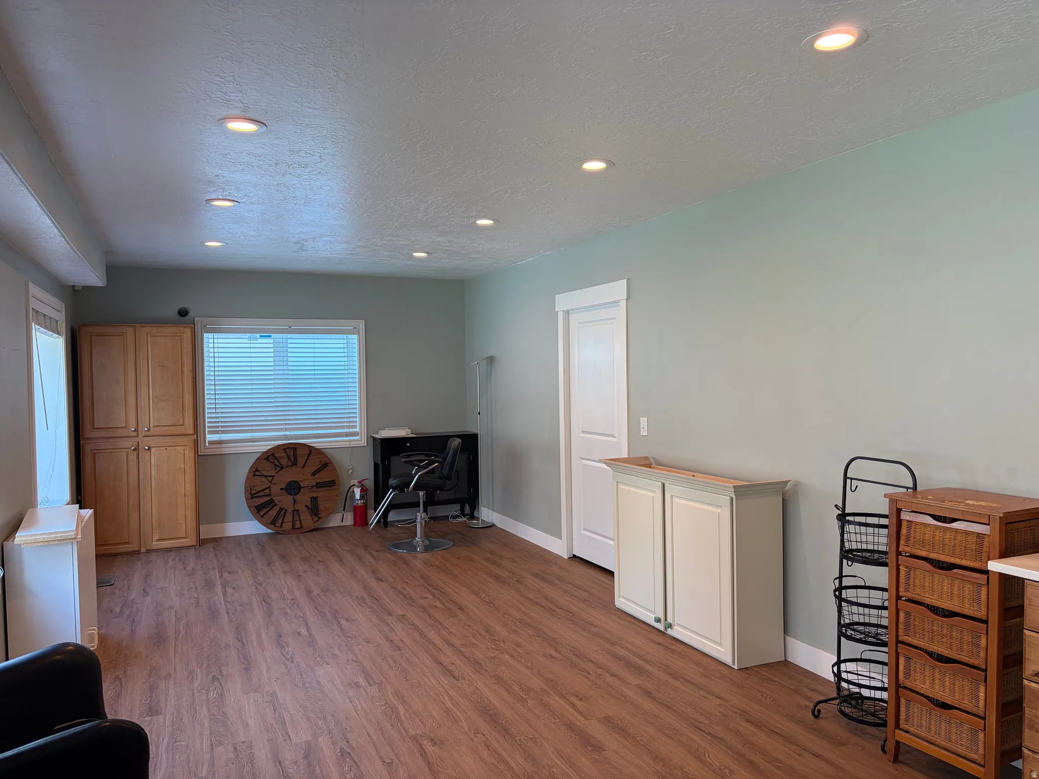 Spacious interior room with wood-finish flooring, recessed lighting, and light green walls