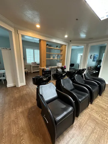 Dedicated commercial space featuring multiple shampoo stations, wood-finish flooring, recessed lighting, built-in shelving, and white plantation shutters