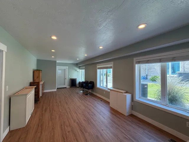 Spacious room featuring wood-finish flooring, recessed lighting, and multiple windows
