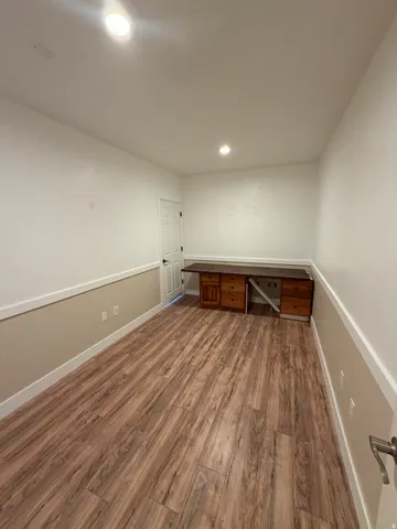 Spacious room featuring wood-finish flooring, recessed lighting, and a neutral two-tone wall scheme with white trim