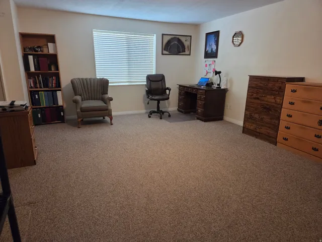 Spacious room with light-colored walls and neutral carpeting