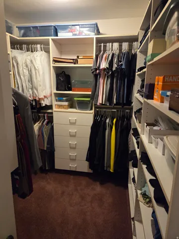 Custom-built walk-in closet system featuring white cabinetry, multiple hanging rods, integrated shelving, and a five-drawer dresser