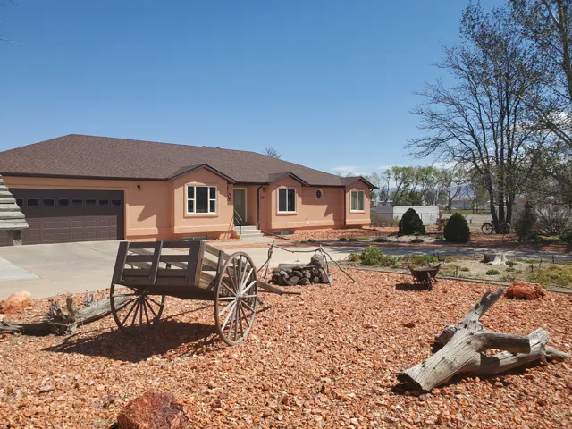 Ranch-style residence featuring a brown asphalt shingle roof, tan stucco exterior, and an attached two-car garage with a brown door
