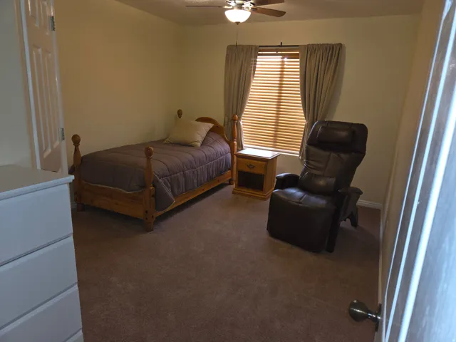 Carpeted room with a ceiling fan light fixture, window with blinds and drapes, and a white paneled door