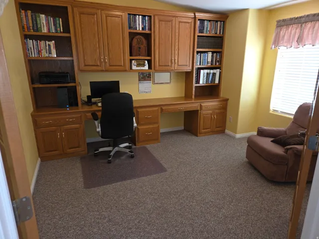 Built-in wood cabinetry with integrated desk and shelving, complemented by a window with blinds