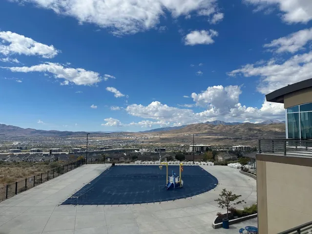 Outdoor pool area featuring a dark blue pool cover, surrounding concrete patio, and security fencing