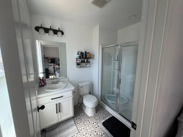 Bathroom featuring a white vanity with an undermount sink, a framed mirror, and a three-light fixture
