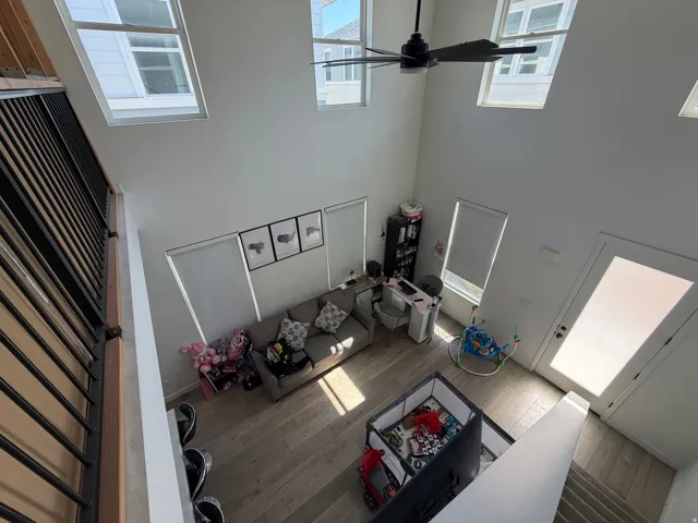 Living area featuring a high ceiling, multiple large windows, and wood-finish flooring