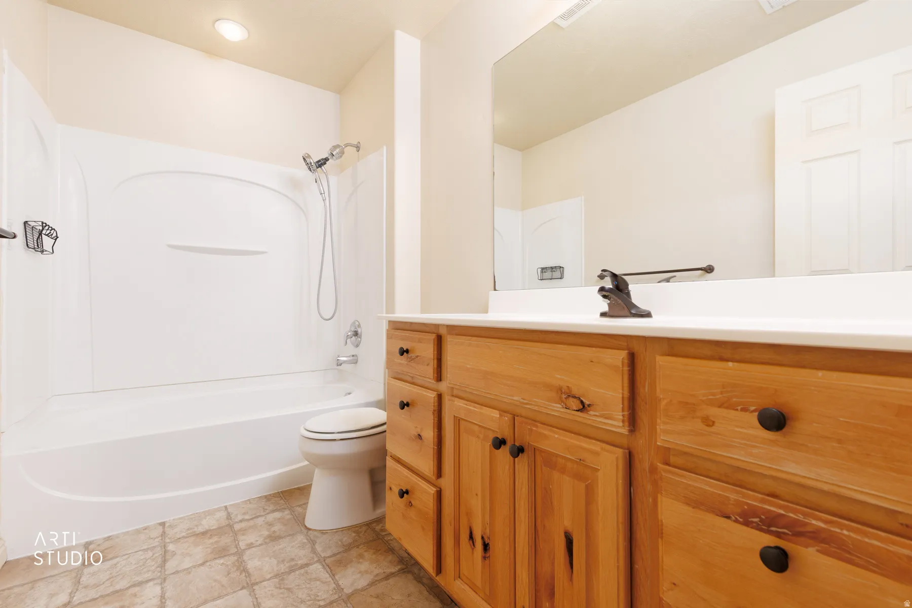 Bathroom featuring a wood-finish vanity with a white countertop, an integrated sink, and an oversized wall mirror