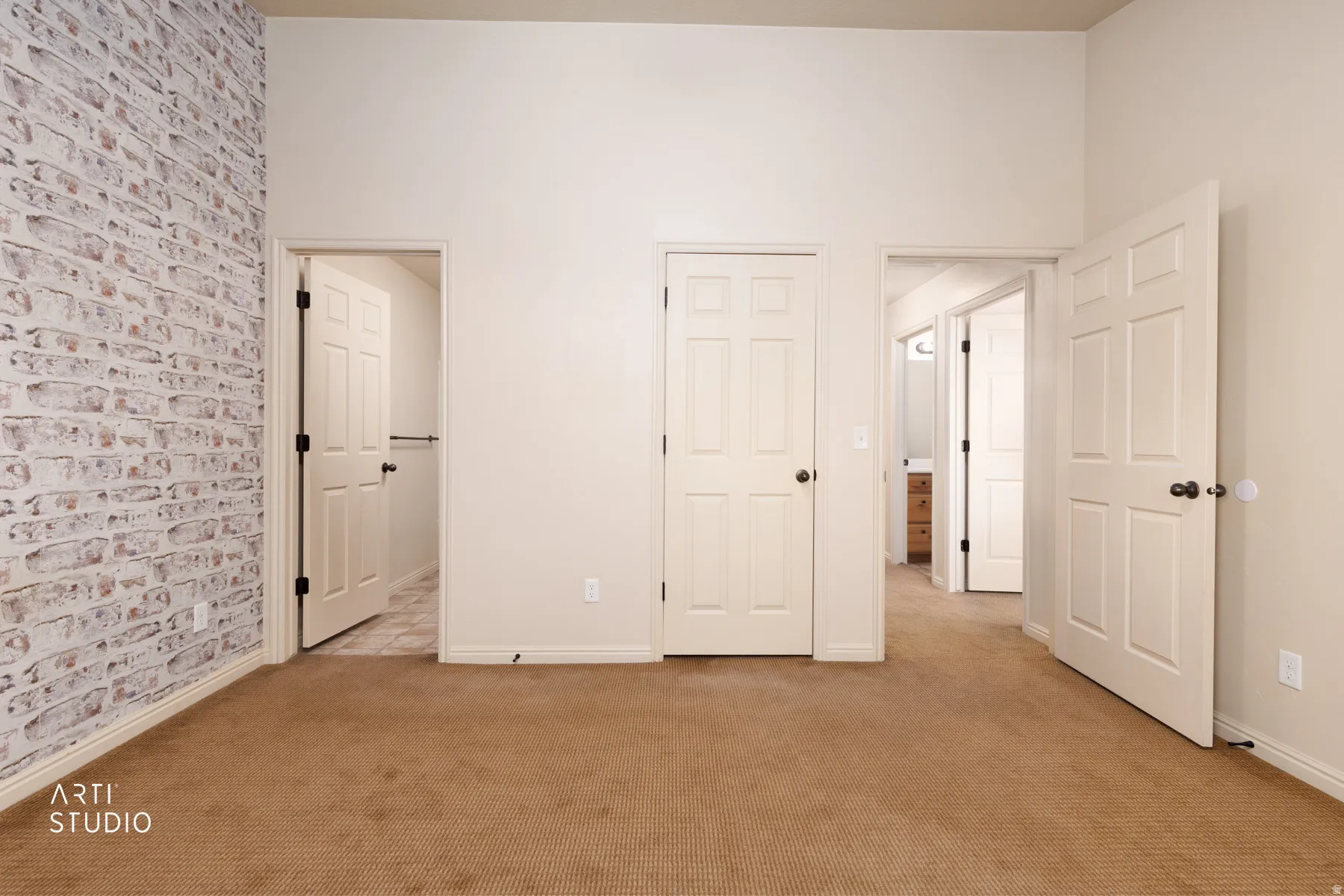 Interior space featuring textured brick-patterned wall, neutral carpeting, and multiple panel doors