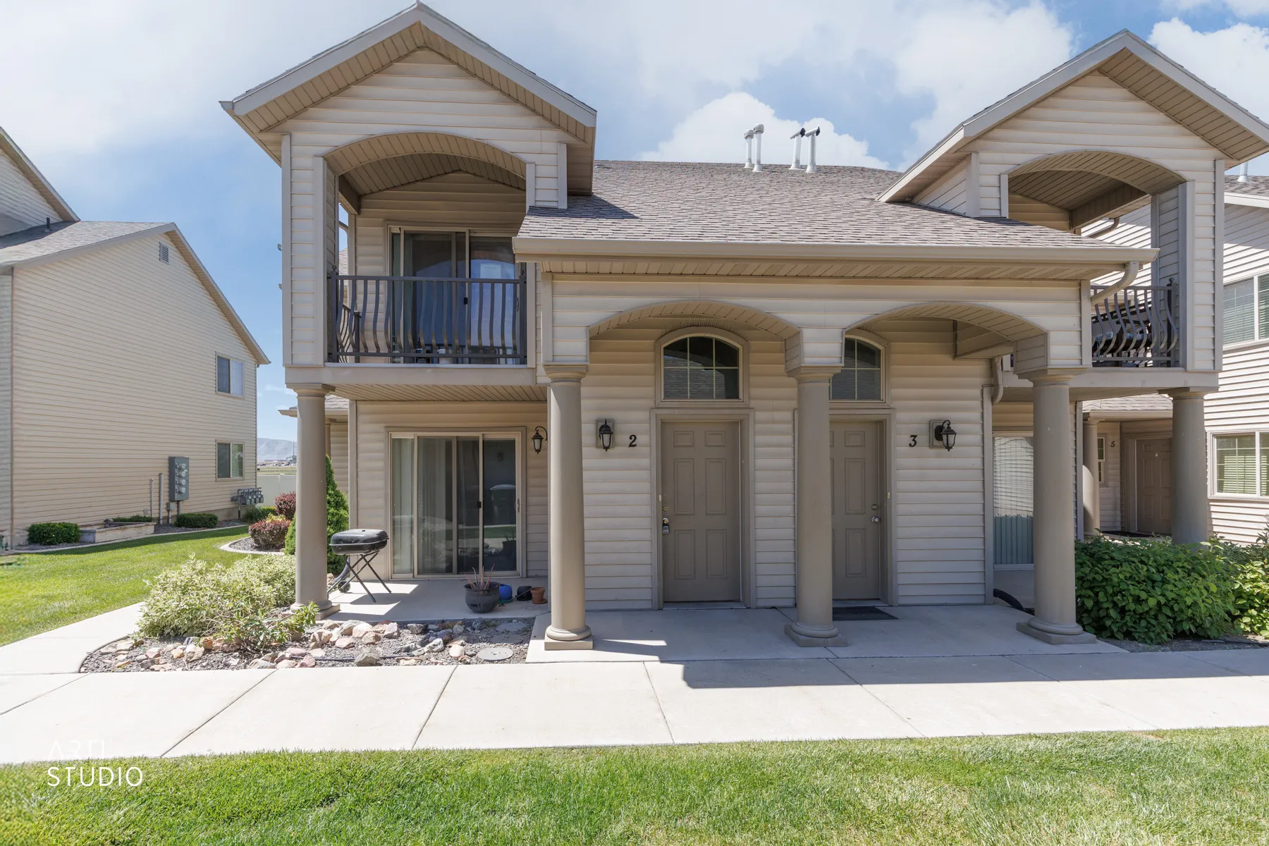Multi-unit exterior with light-toned siding and a shingle roof