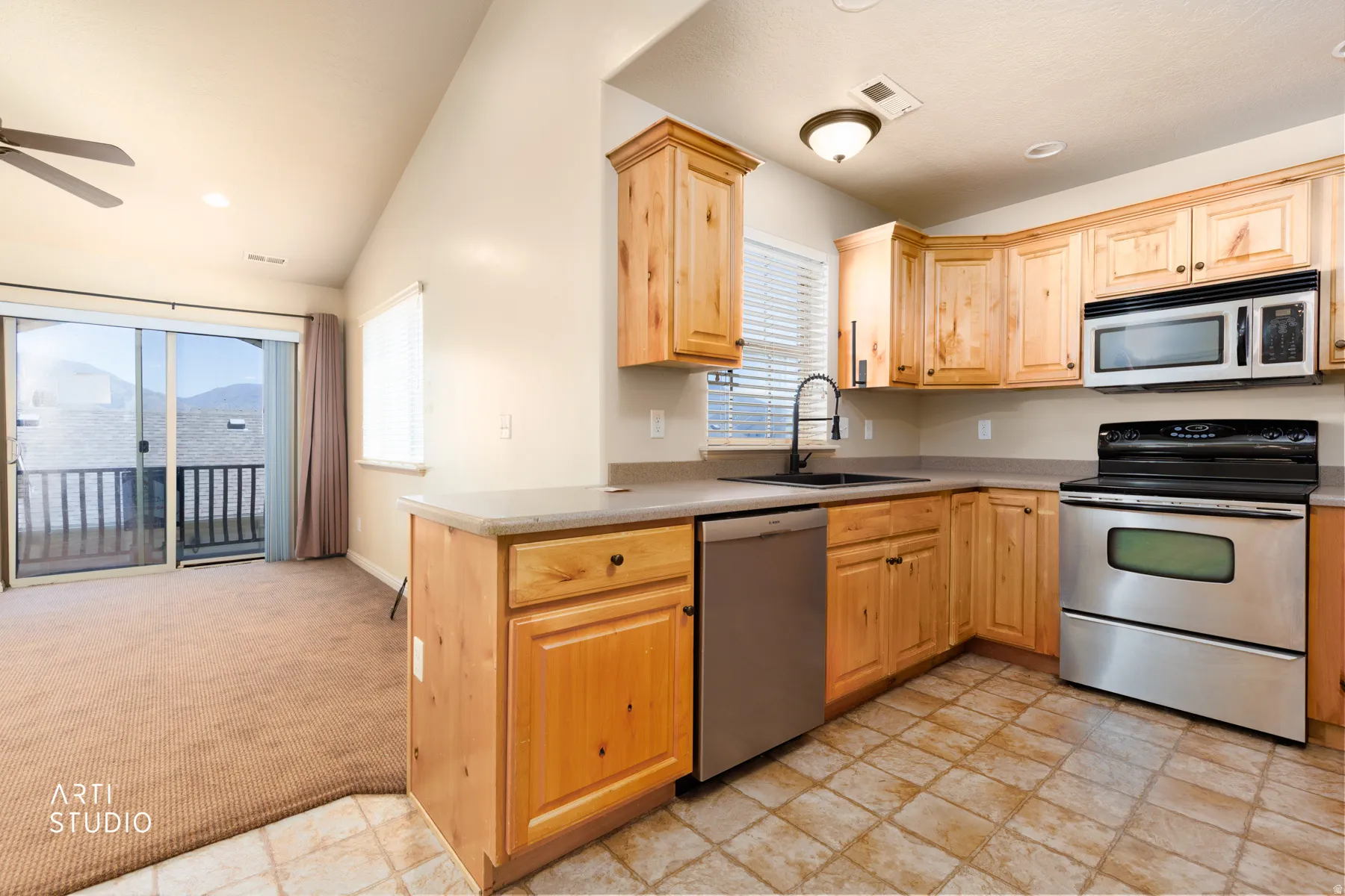 Kitchen featuring wood cabinetry, stainless steel appliances, a black faucet, and patterned floor tiling