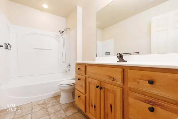 Bathroom featuring a wood-finish vanity with a white countertop, an integrated sink, and an oversized wall mirror
