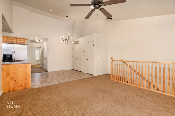 Open-concept living area with vaulted ceilings, a modern sputnik chandelier, and a ceiling fan