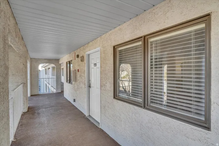 Covered exterior walkway featuring stucco walls and a white paneled ceiling