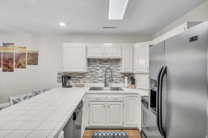 Kitchen featuring white cabinetry, a tiled countertop, and a mosaic tile backsplash