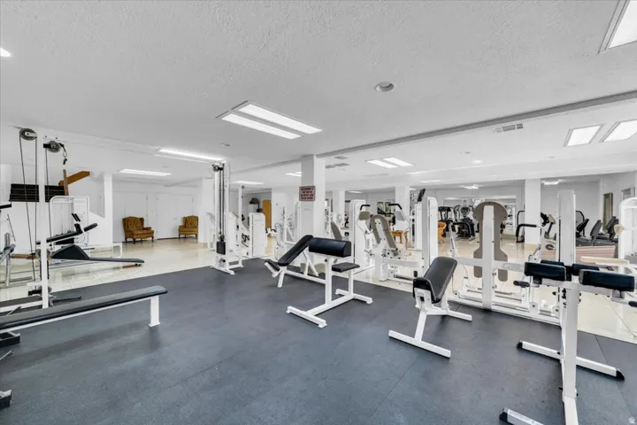 Spacious fitness center featuring a variety of exercise equipment, mirrored walls, and recessed lighting