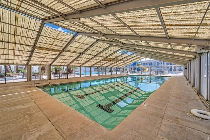 Enclosed swimming pool facility featuring a translucent slatted roof, concrete decking, and a lap lane marked pool