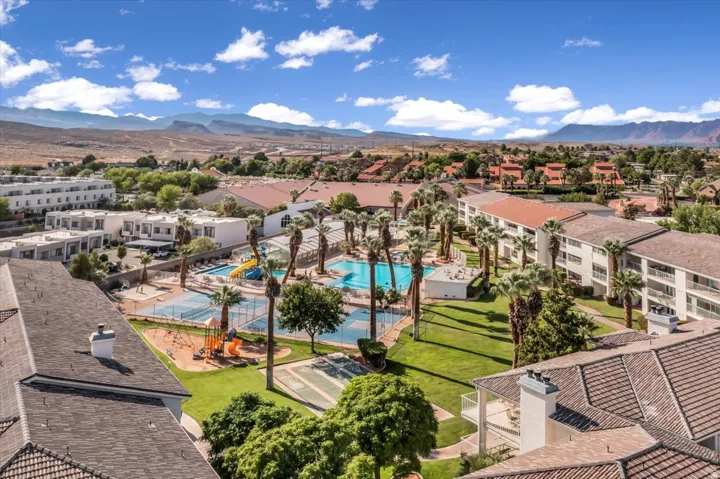 Expansive community grounds featuring multiple swimming pools, sports courts, a playground, and abundant palm trees