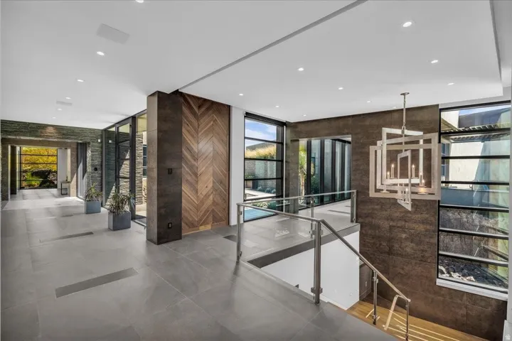 Contemporary interior foyer featuring expansive tile flooring, a geometric chandelier, and a wood-panel accent wall