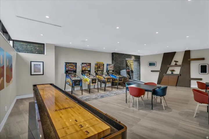 Spacious recreational room featuring light wood-finish flooring, recessed lighting, and a shuffleboard table