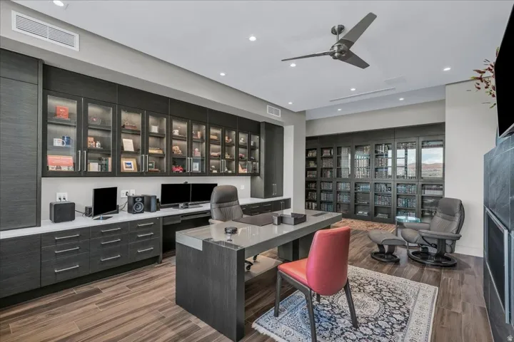 Dedicated office space featuring extensive built-in cabinetry with glass-front uppers and task lighting