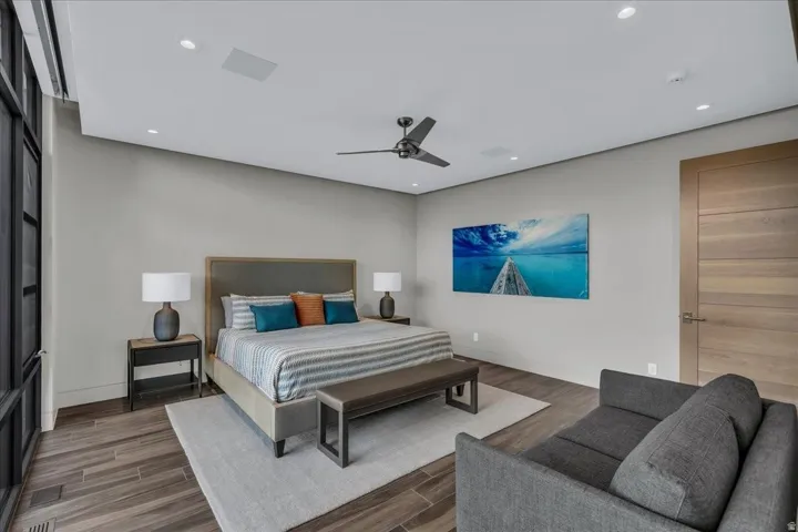 Spacious bedroom featuring wood-finish flooring, a contemporary ceiling fan, recessed lighting, and a paneled interior door
