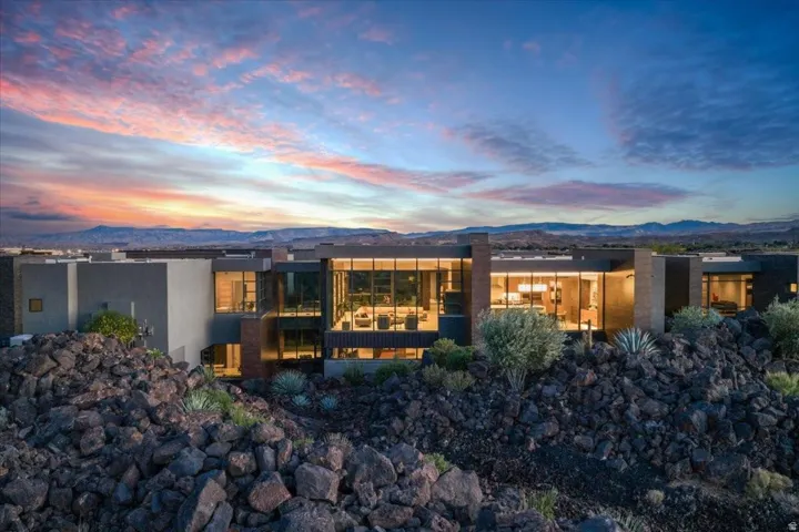 Contemporary architecture featuring extensive floor-to-ceiling windows, multiple balconies, a flat roofline, and a stucco exterior with stone accents