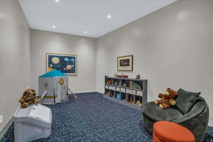 Spacious room featuring neutral painted walls, recessed lighting, blue patterned carpeting, and white baseboards