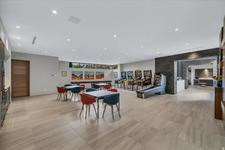 Spacious recreation room featuring large format tile flooring, recessed lighting, and a built-in wet bar with stainless steel appliances