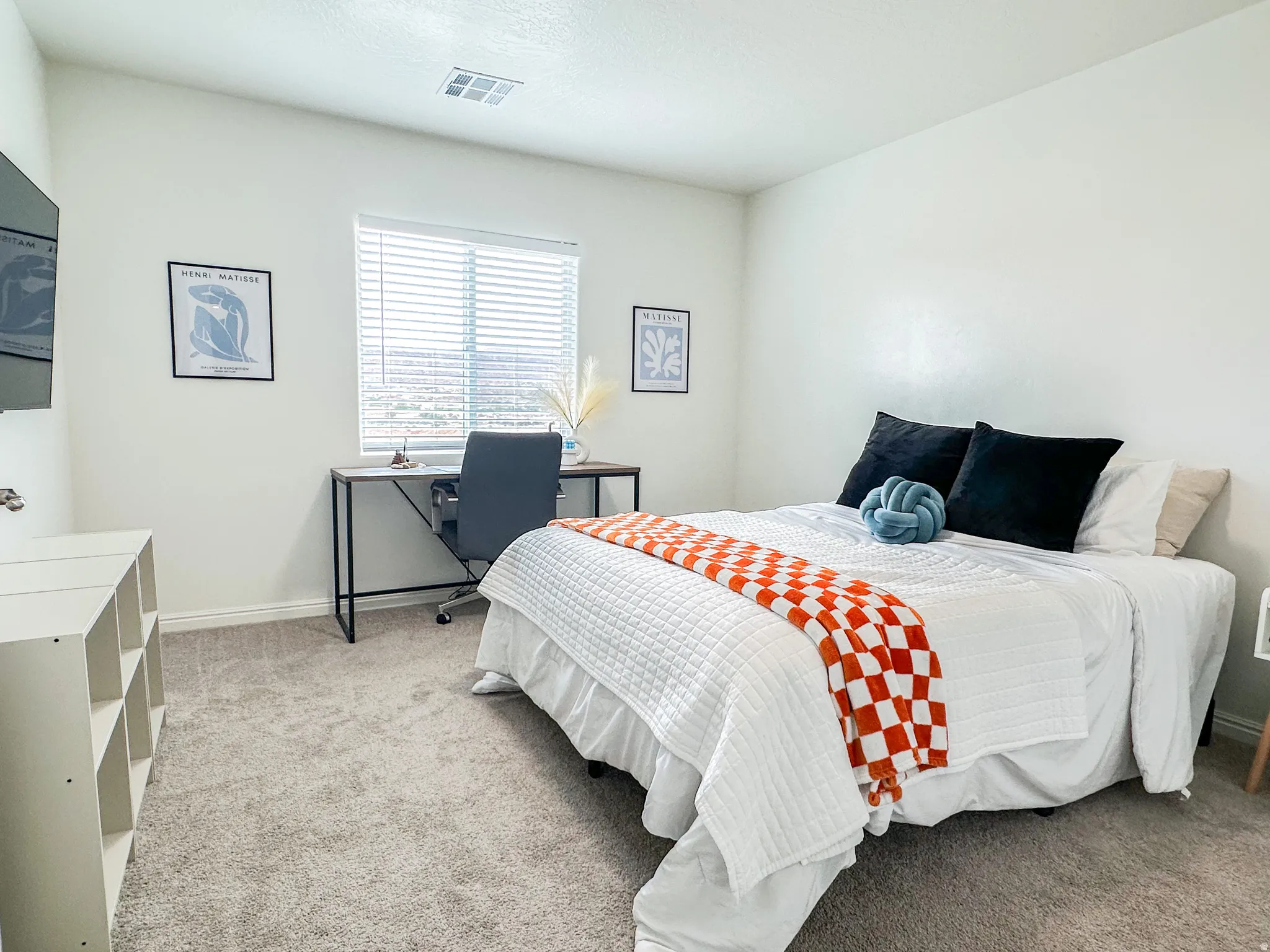 Carpeted bedroom featuring white walls and a large window with horizontal blinds