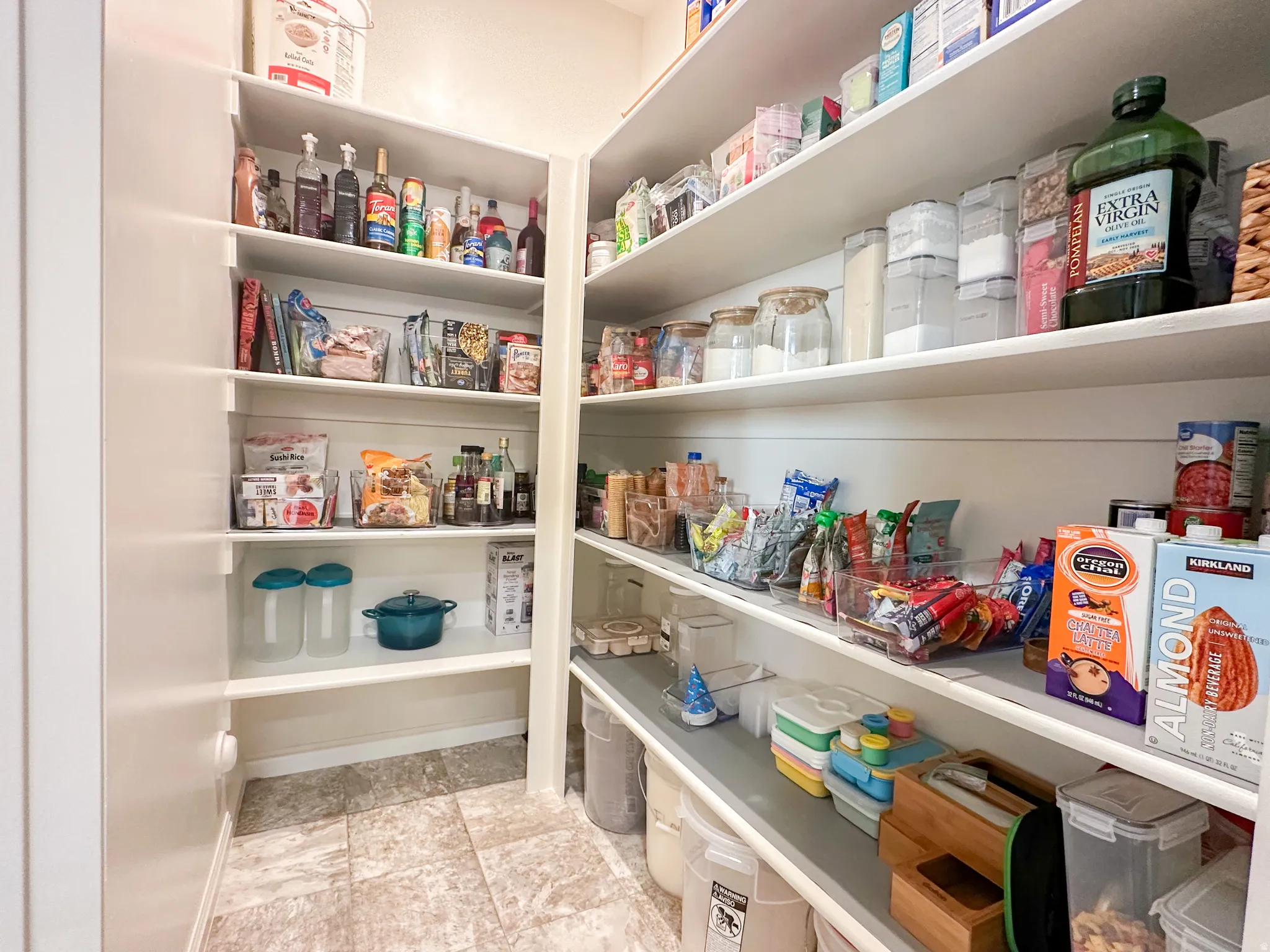 Spacious pantry featuring extensive shelving, white cabinetry, and tile flooring