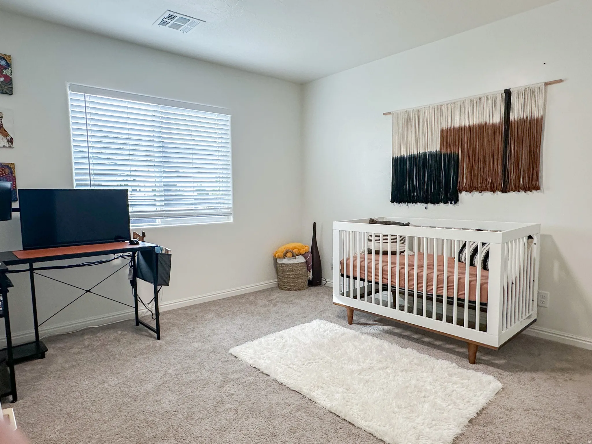 Carpeted room featuring a white baseboard, a window with horizontal blinds, and a ceiling-mounted HVAC vent