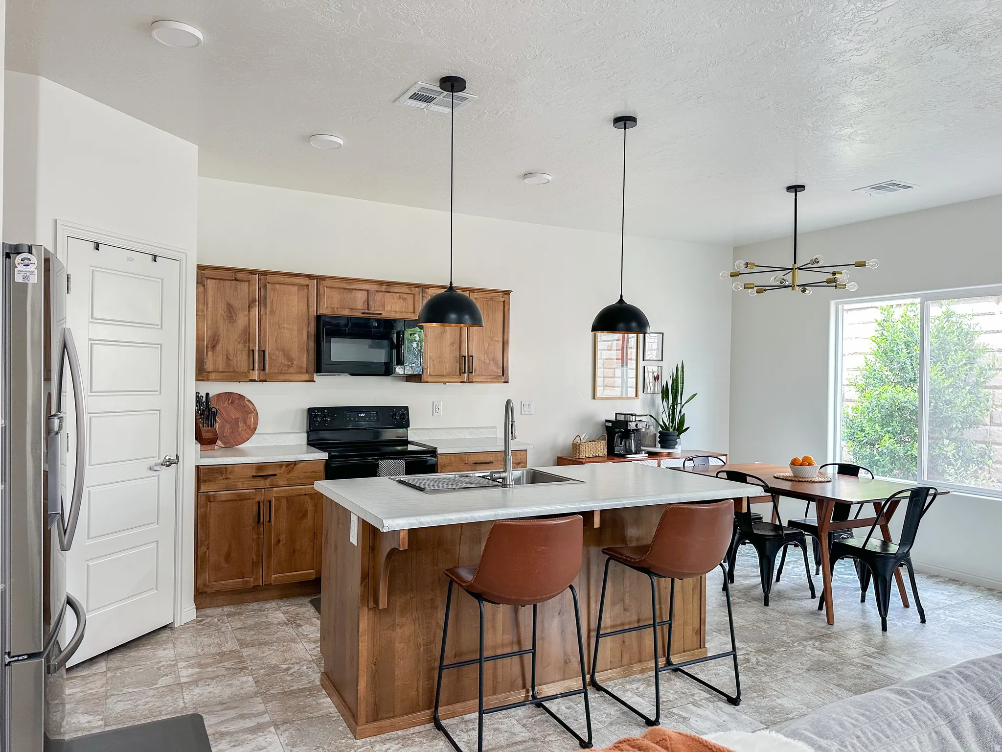 Open-concept kitchen and dining area featuring wood cabinetry, light countertops, and tile-finish flooring