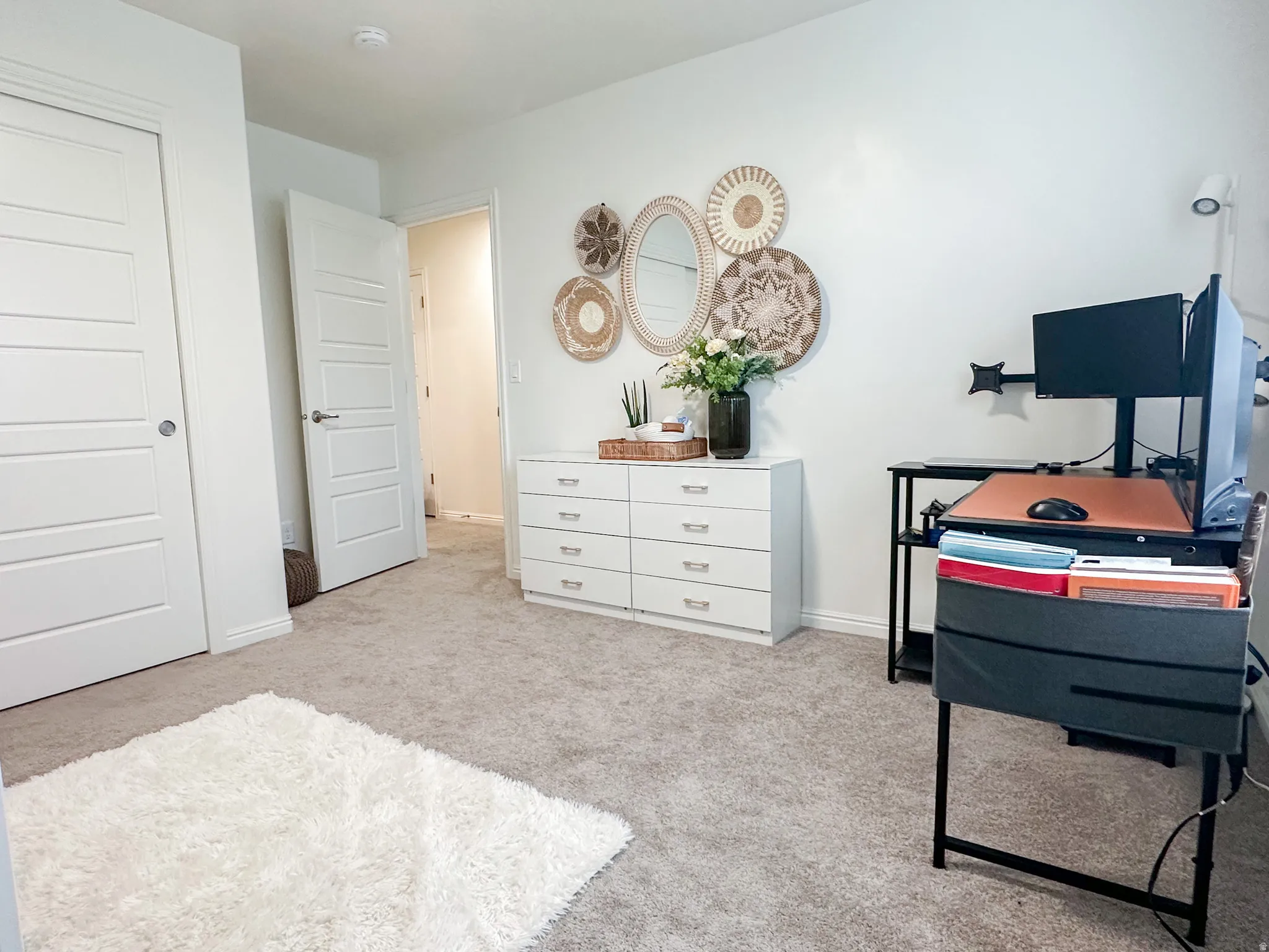 Carpeted room with white walls, featuring a six-drawer dresser with metal pull handles, and a white interior door with horizontal paneling