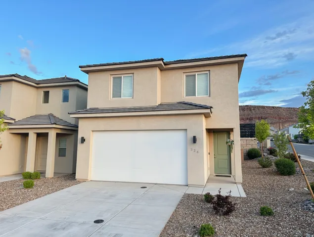 Contemporary stucco exterior with an attached garage, a light green front door, and a concrete driveway