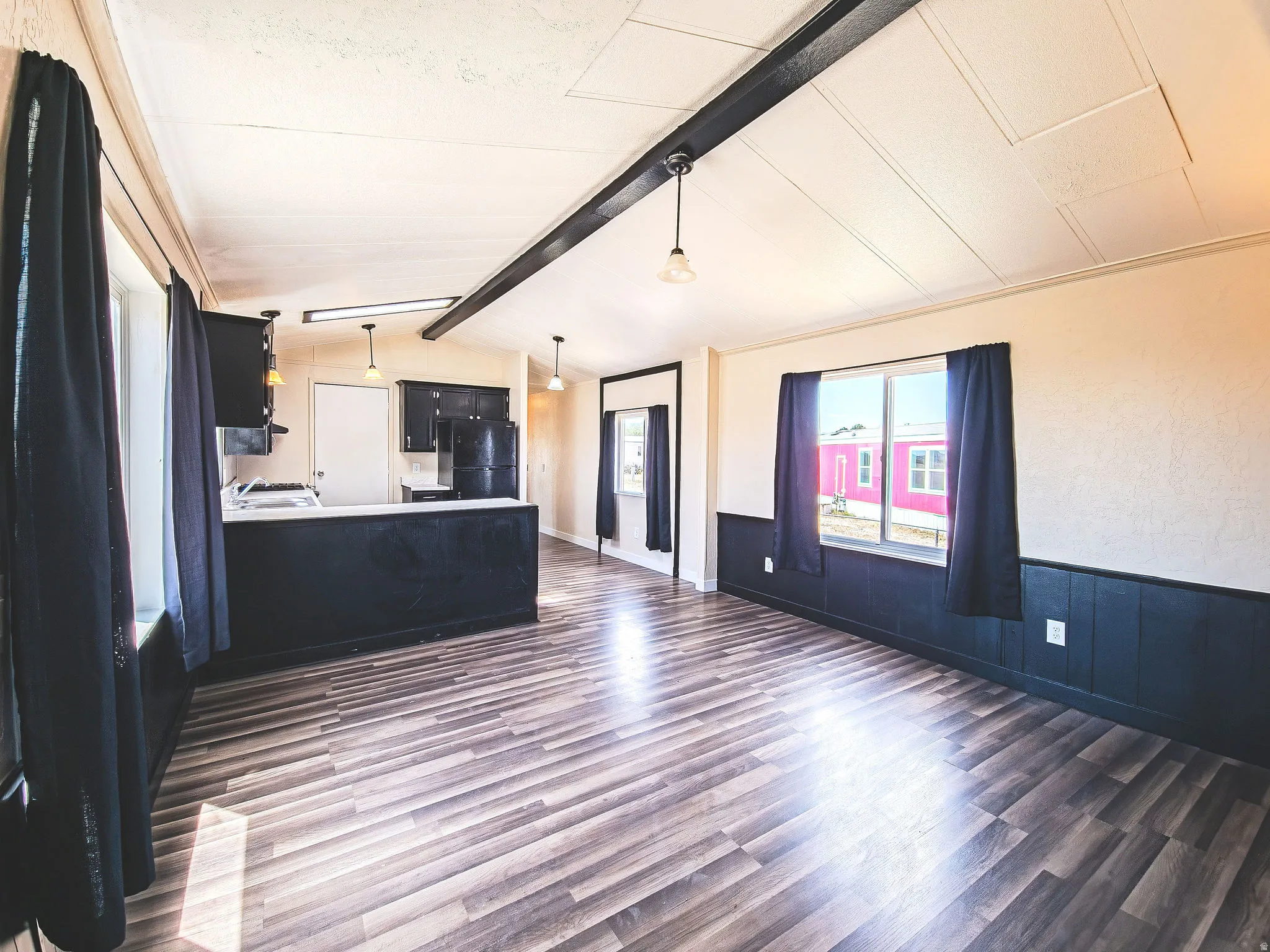 Open-concept living space featuring wood-finish flooring, white walls, and dark wainscoting