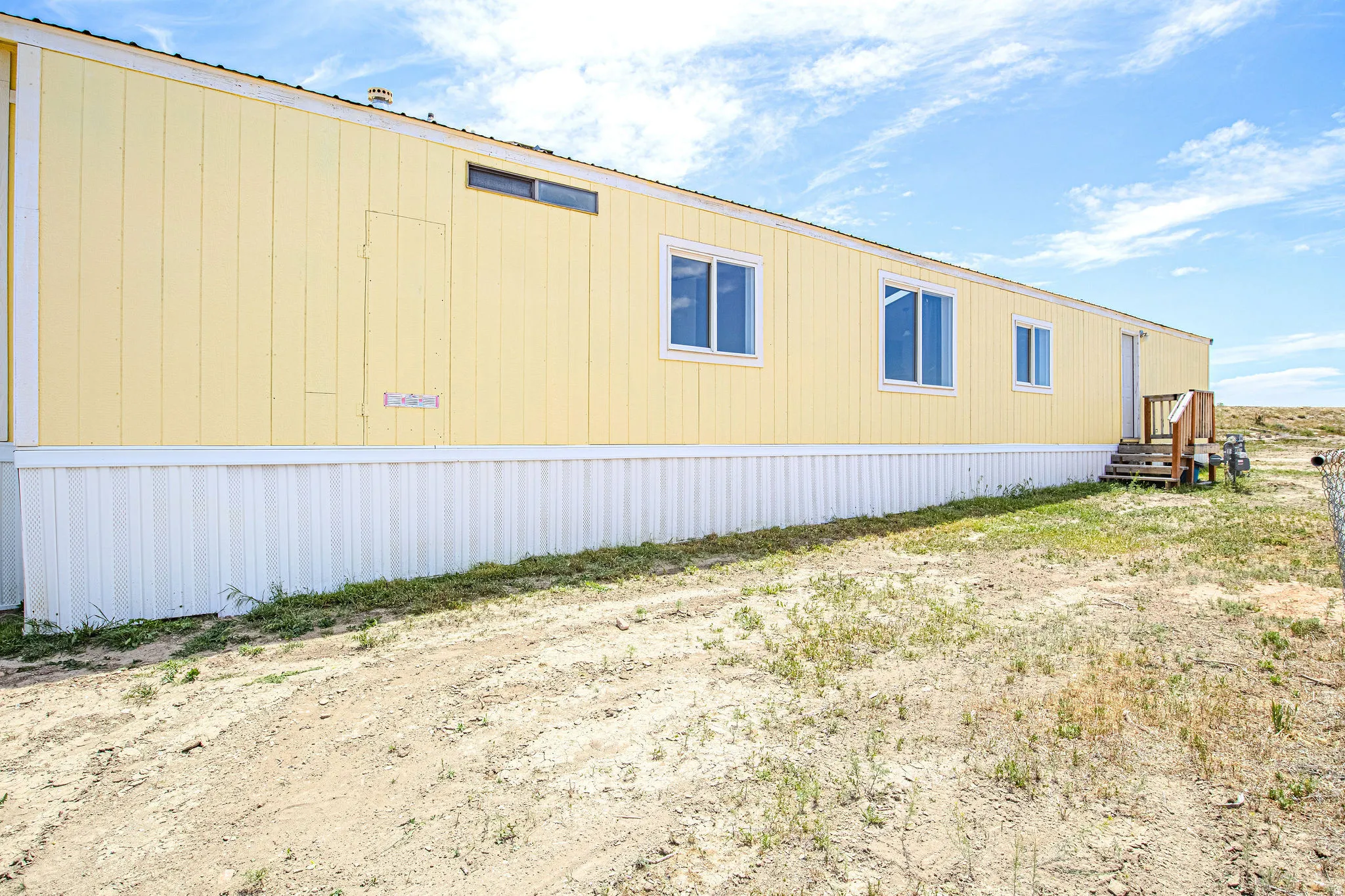 Yellow panel siding with multiple windows and white trim