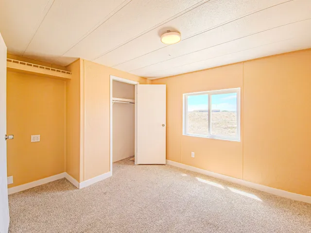 Room featuring neutral-toned carpeting, light orange walls, and white trim