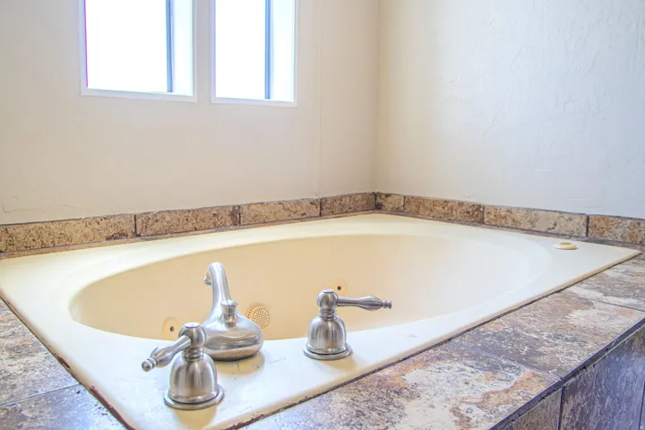 Built-in soaking tub with brushed nickel fixtures and a tiled surround