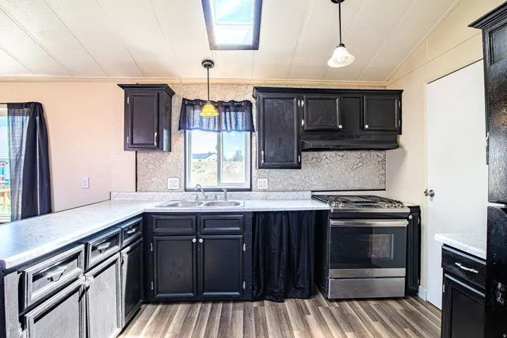 Kitchen featuring dark cabinetry, light countertops, wood-finish flooring, and a skylight