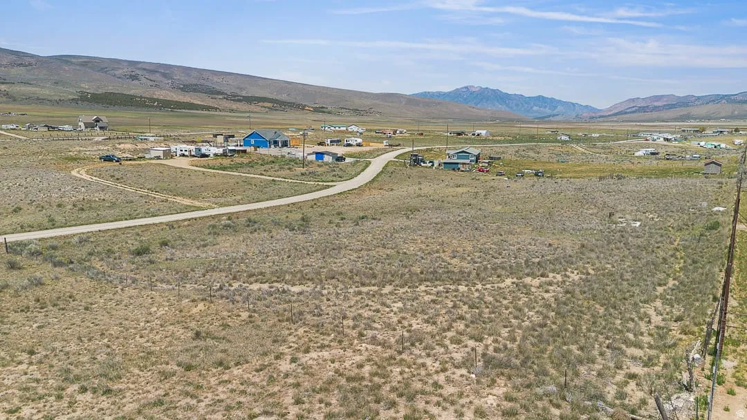 Expansive undeveloped land featuring varied scrub brush and a distant mountain range backdrop
