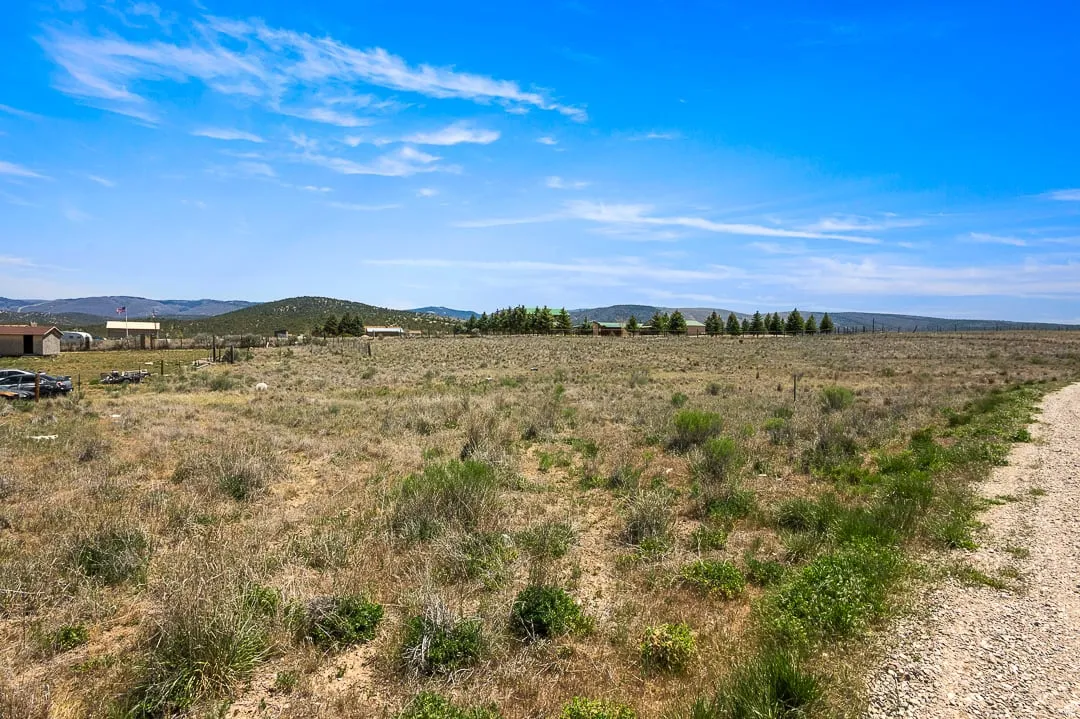 Expansive undeveloped land featuring sparse vegetation and distant structures