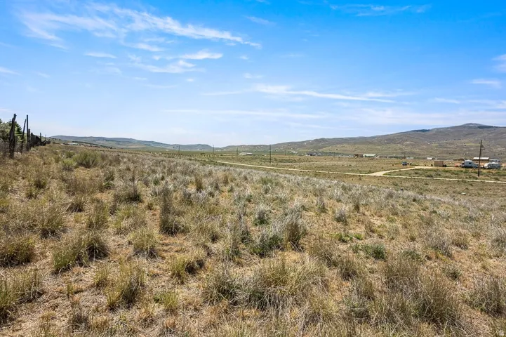 Expansive rural property featuring a distant mountain range and a clear blue sky