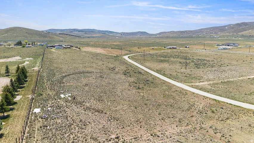 Expansive undeveloped land featuring a paved road, scattered vegetation, and distant mountain ranges