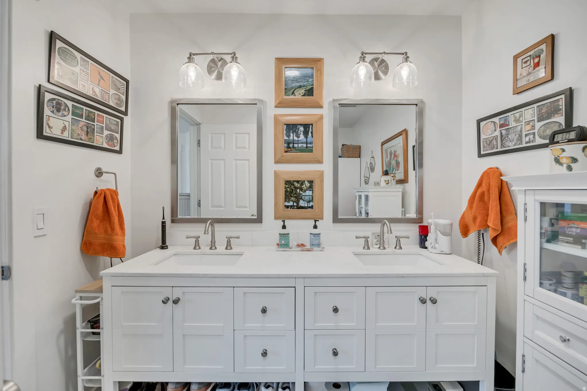 Dual vanity with white cabinetry, integrated sinks, brushed nickel fixtures, and coordinating framed mirrors