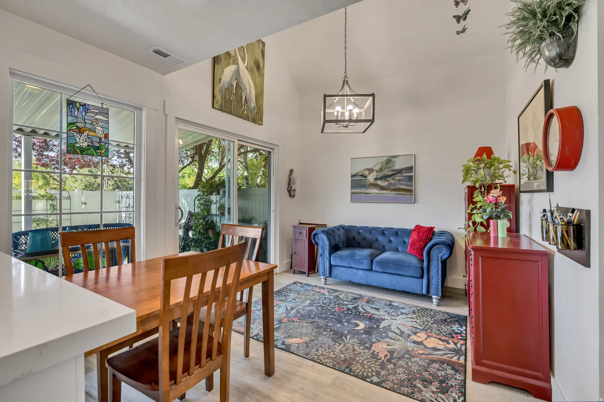 Vaulted ceiling with exposed beam, wood-finish flooring, and natural light from large windows and a sliding glass door