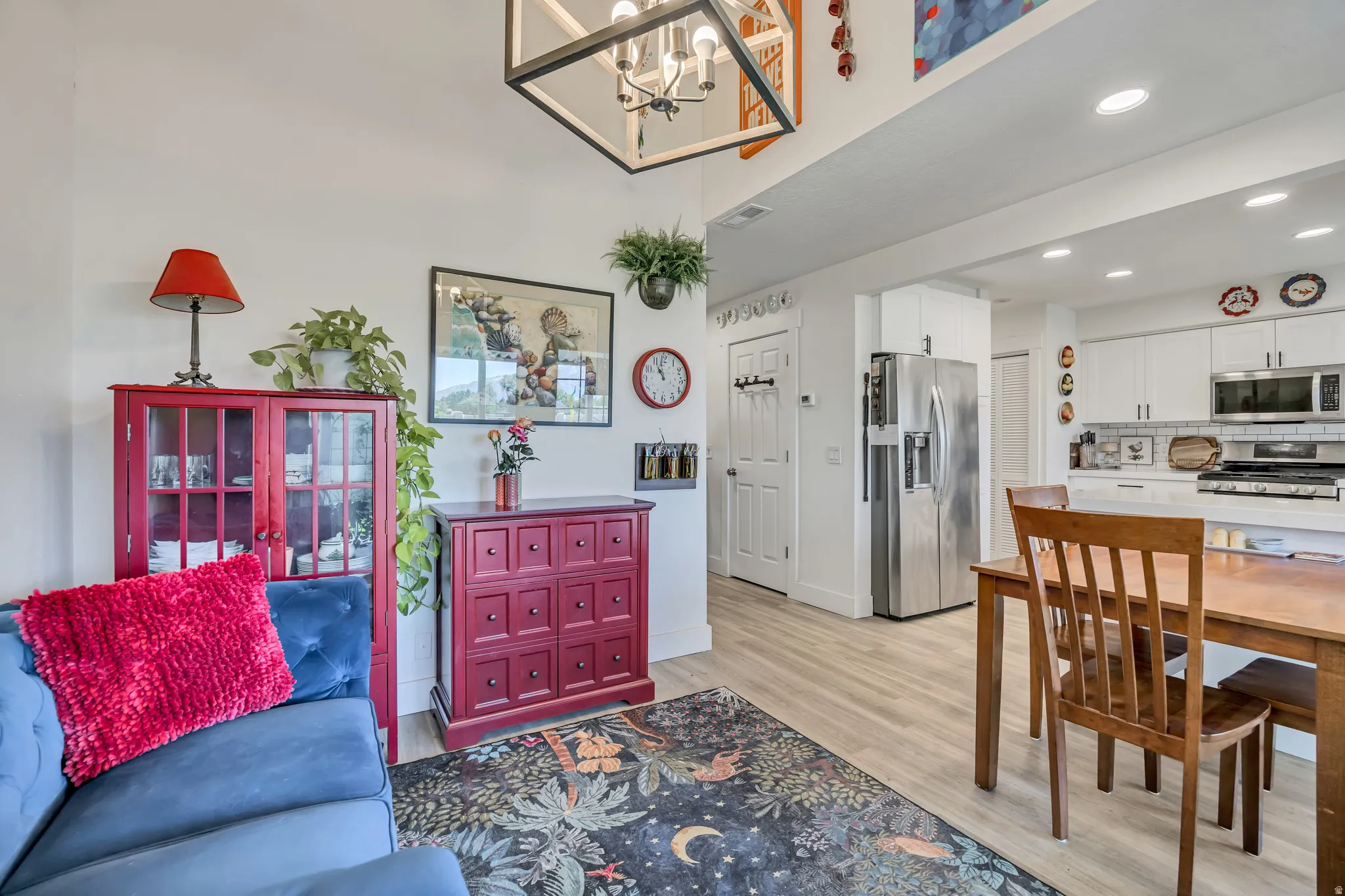 Open concept living area featuring light wood-finish flooring, a contemporary chandelier, and high ceilings