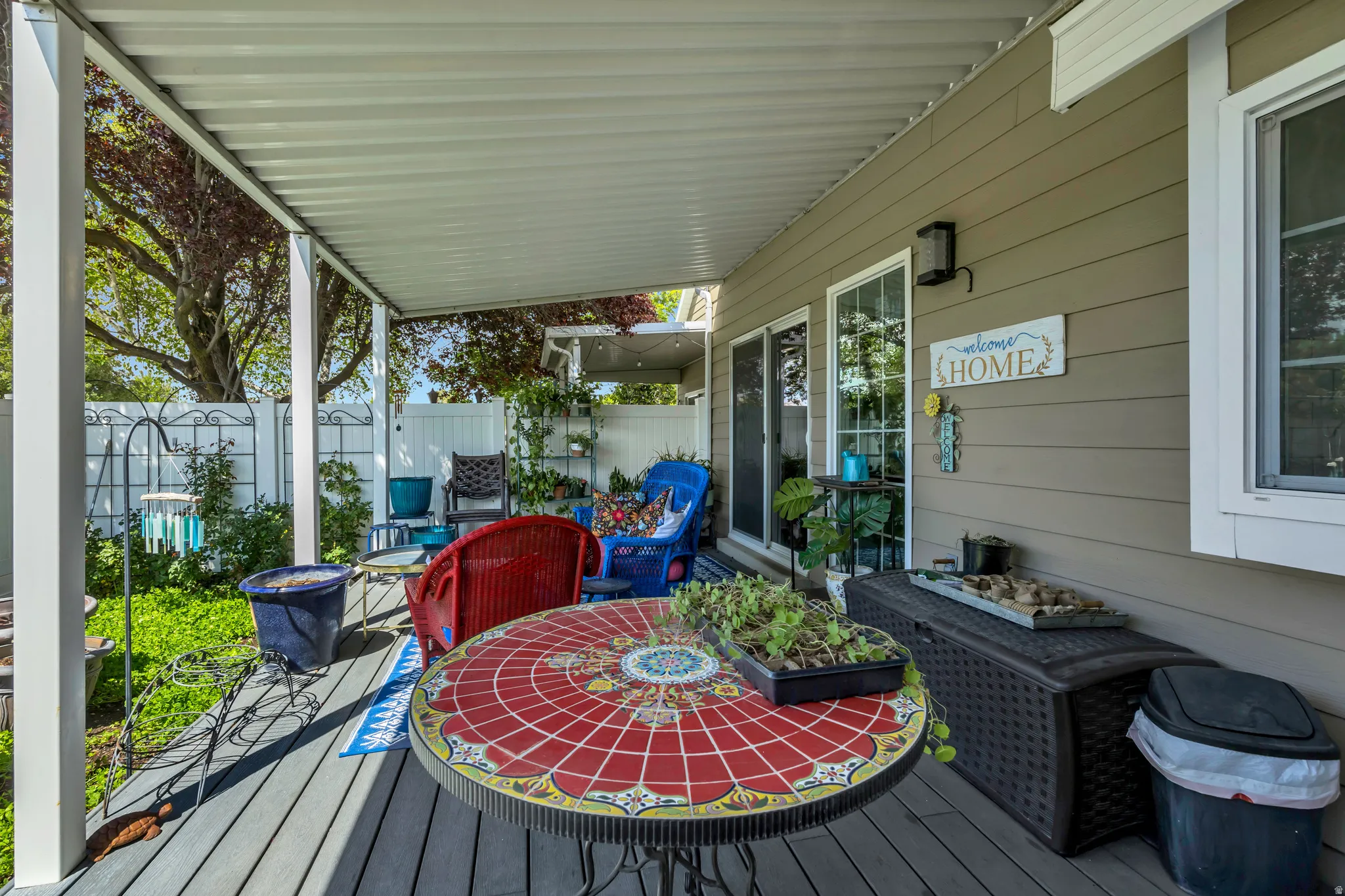 Covered patio featuring plank decking, white aluminum posts, and an overhead awning