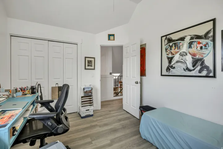 Interior room featuring wood-finish flooring, white walls, and a vaulted ceiling